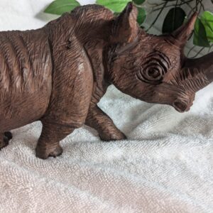 Handcrafted brown wooden rhino figurine with intricate carving details, showcasing rustic charm and skilled artistry in a lifelike design